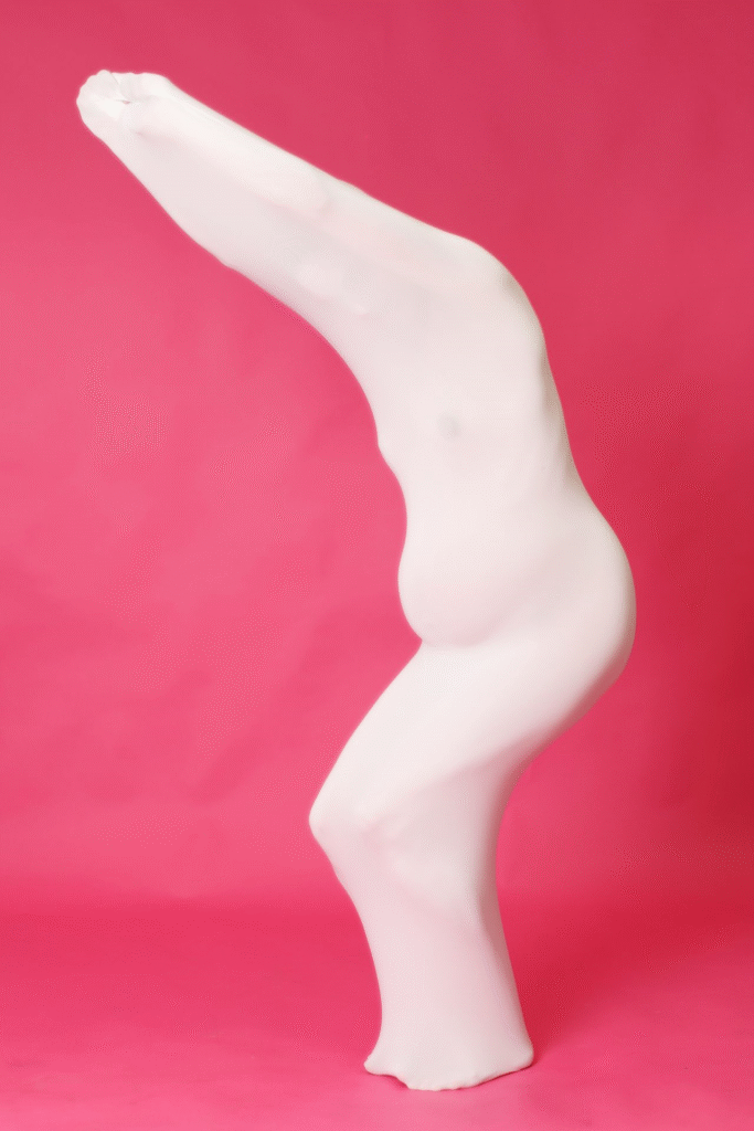 Zeigt schwangere Frau in weissem Kleid vor rosa Hintergrund.